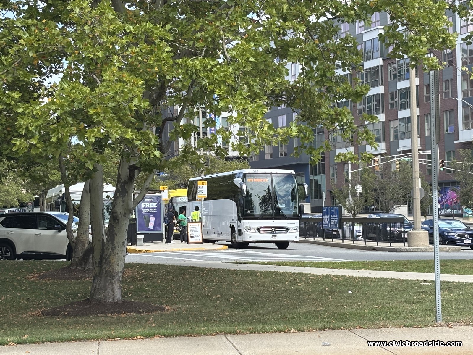 A Vista Grande Line coach bus serving as an Orange Line shuttle, parked at a busway with waiting passengers