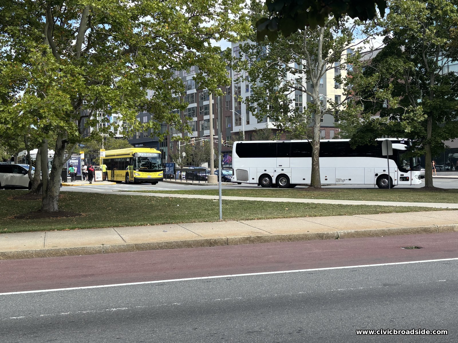 A yellow Tankee Line shuttle bus marked North Station next to a white coach bus