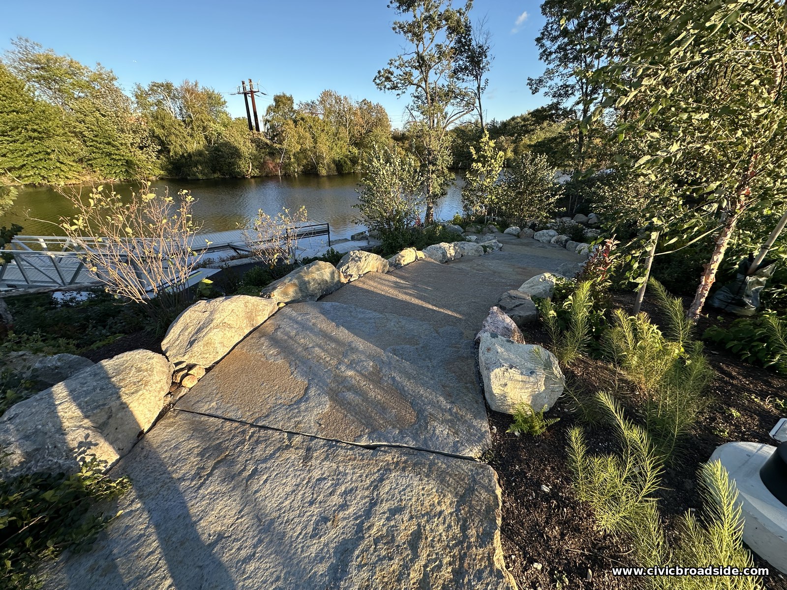 The same stone steps seen from a lower angle, leading toward a white railing at the water's edge