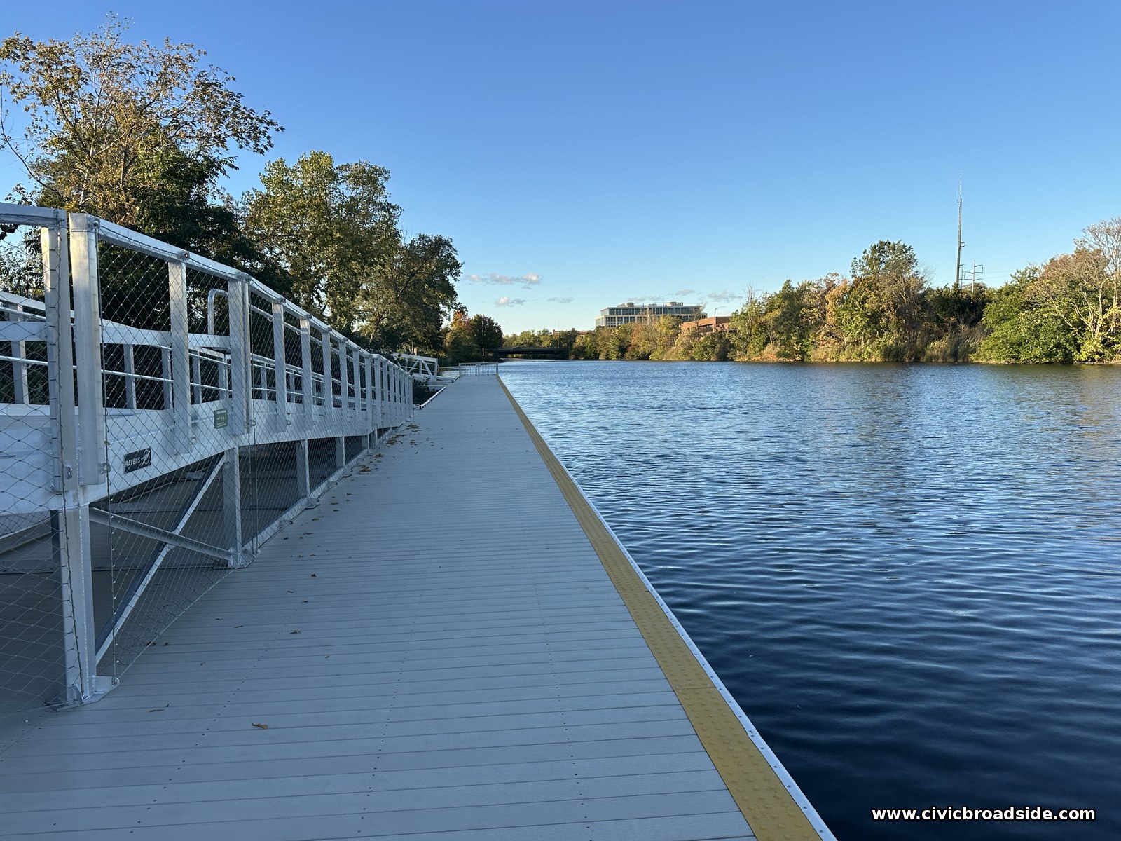 A dock deck with a mesh-railed side on the left and a yellow edge stripe and open water on the right