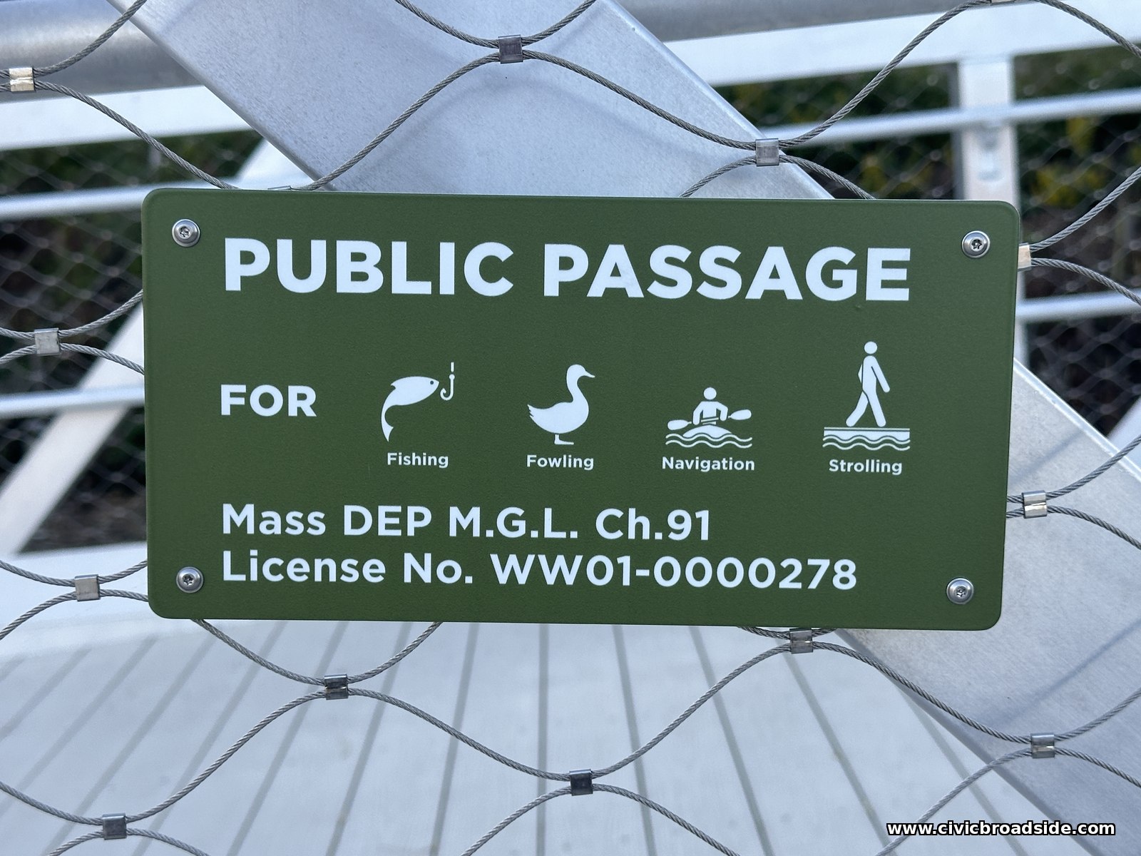 A green sign reading Public Passage for Fishing, Fowling, Navigation, and Strolling, with a Chapter 91 license number, mounted on a steel mesh fence
