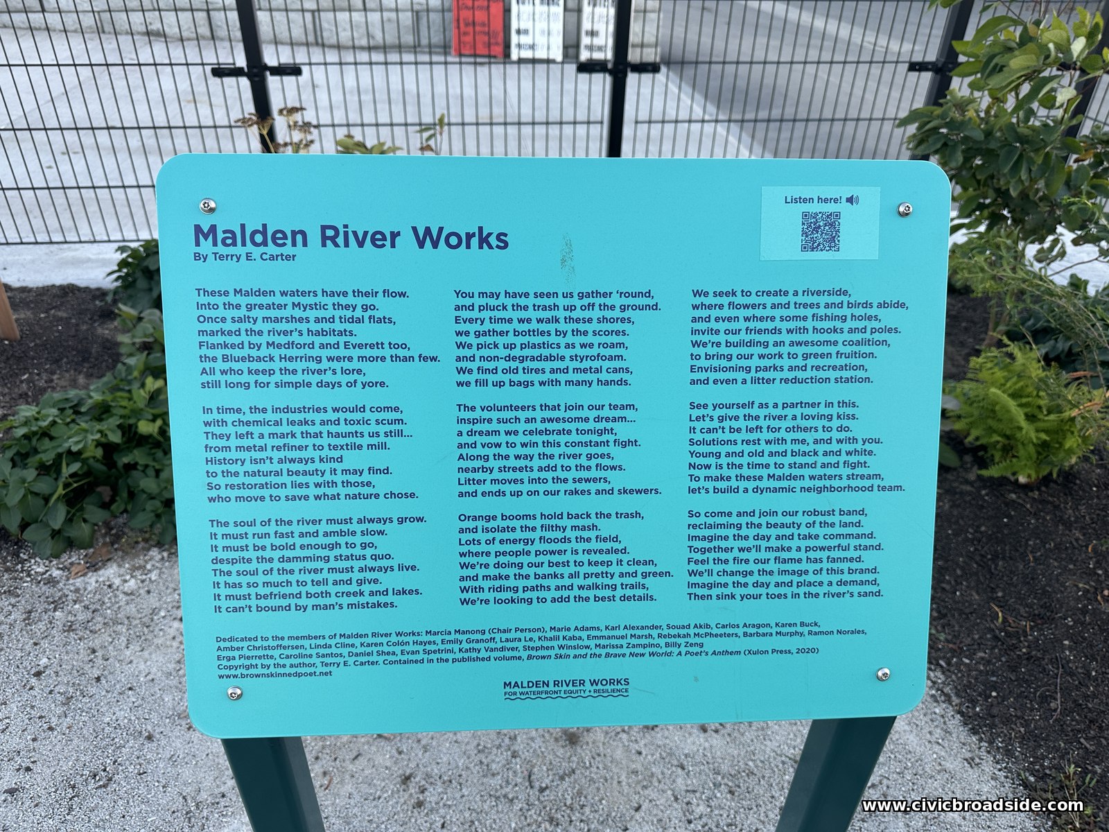 A teal interpretive sign titled Malden River Works, with a poem in three columns and a QR code, mounted on posts beside a black fence